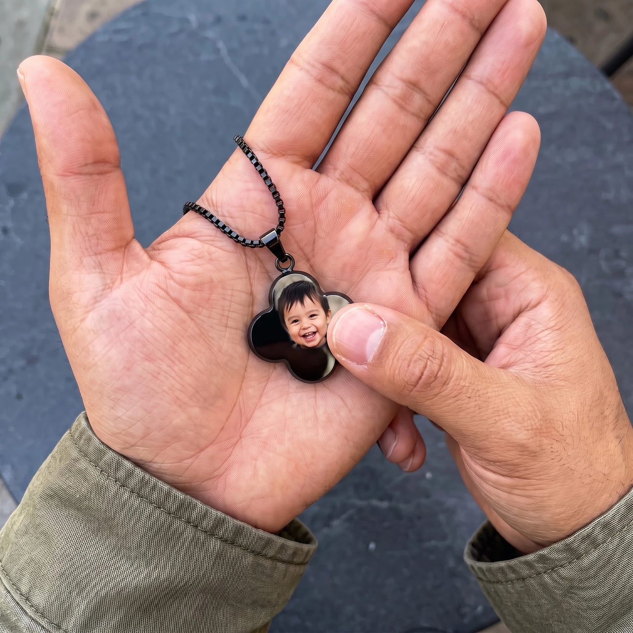 Thumb warming the black clover pendant: the hidden photo appears under the thumb while the rest stays black | SKU: TPH-CLVN-BLACK