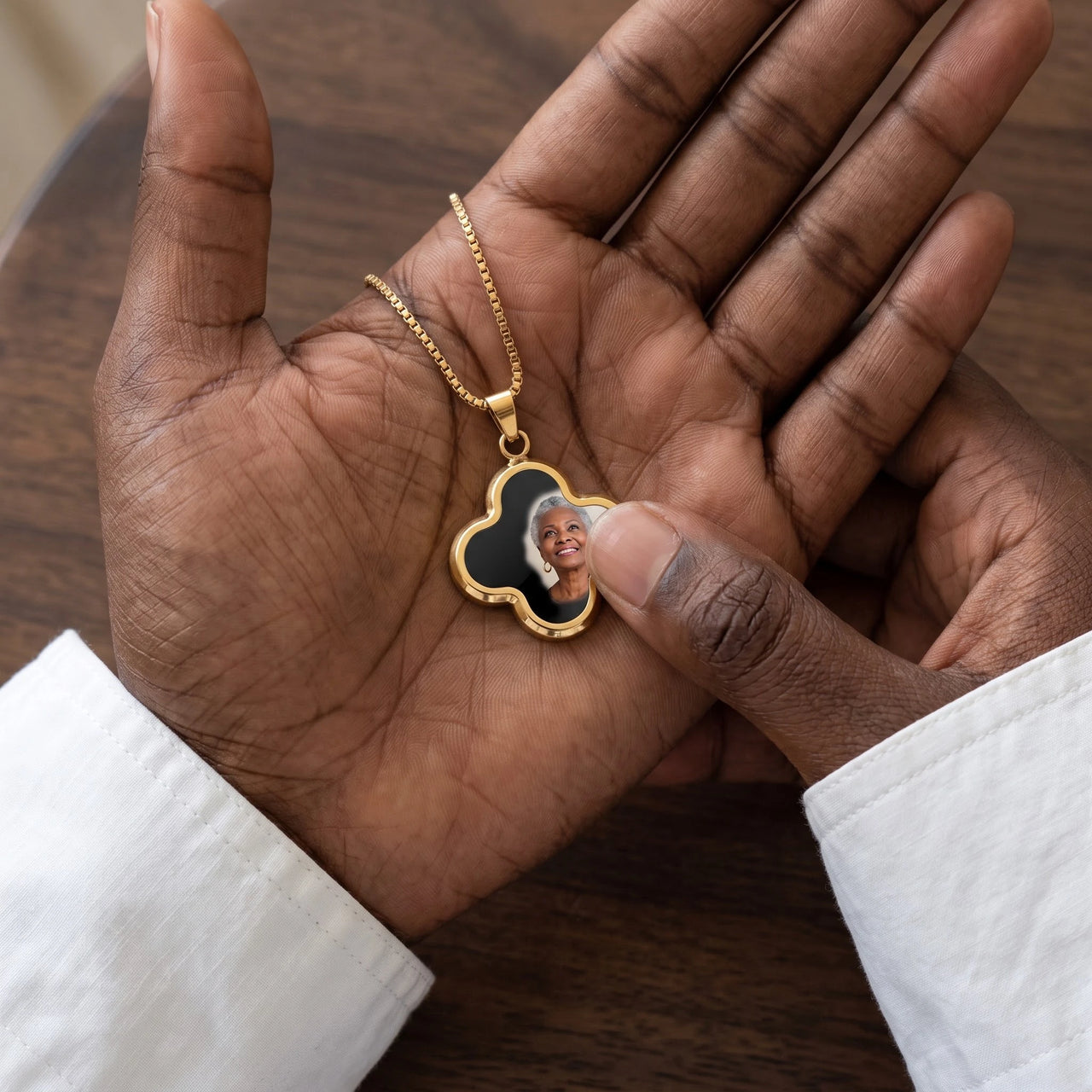 Thumb warming the gold clover pendant: the hidden photo appears under the thumb while the rest stays black | SKU: TPH-CLVN-GOLD